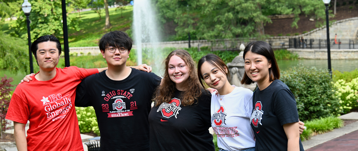 Five students with arms around each other by Mirror Lake