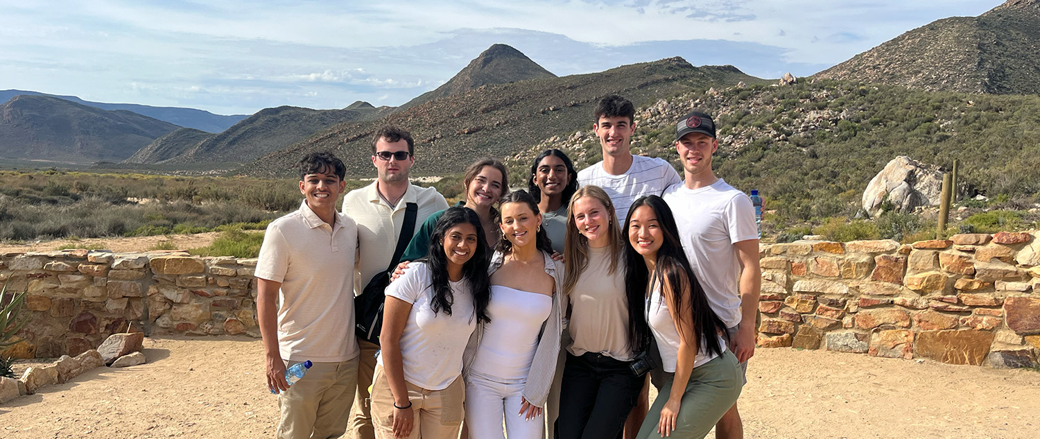 Students posing in front of sandy landscape and mountain