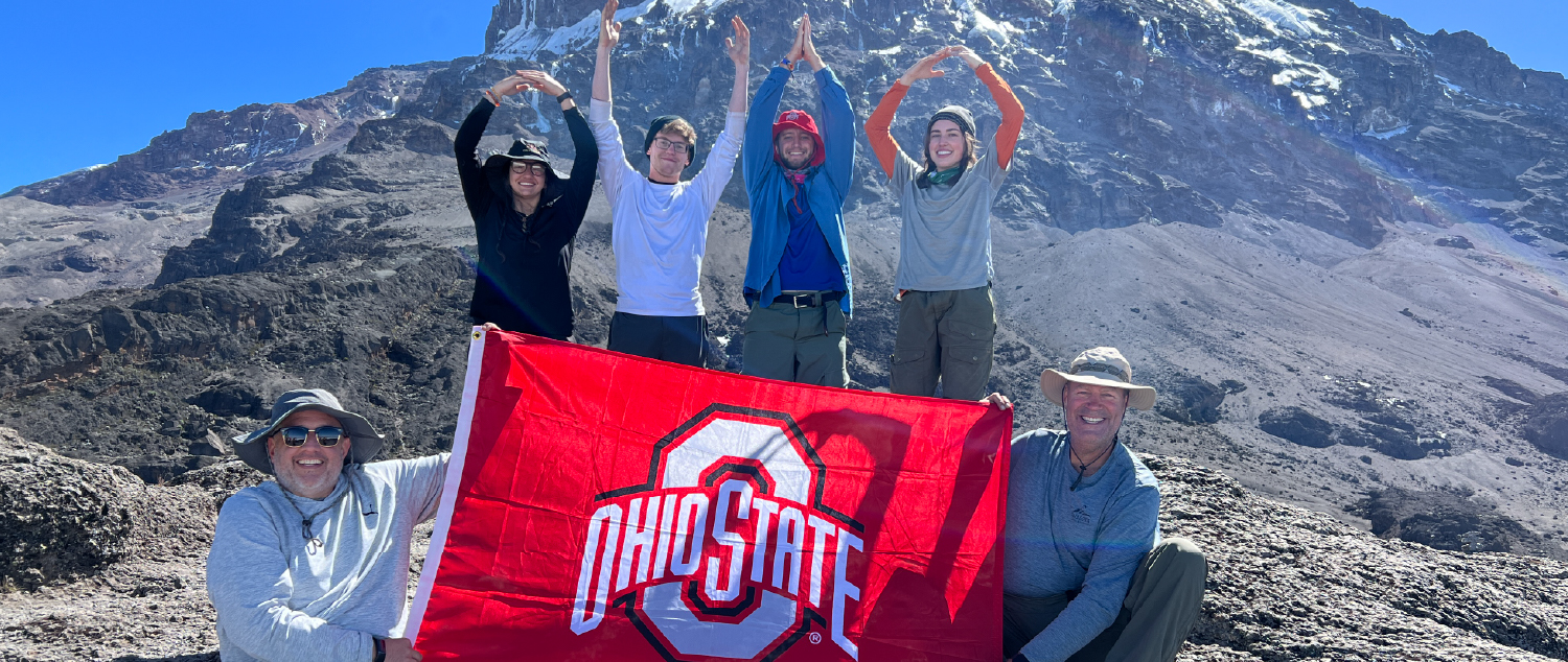 Group of faculty and Students in front of a mountain holding an Ohio State flag