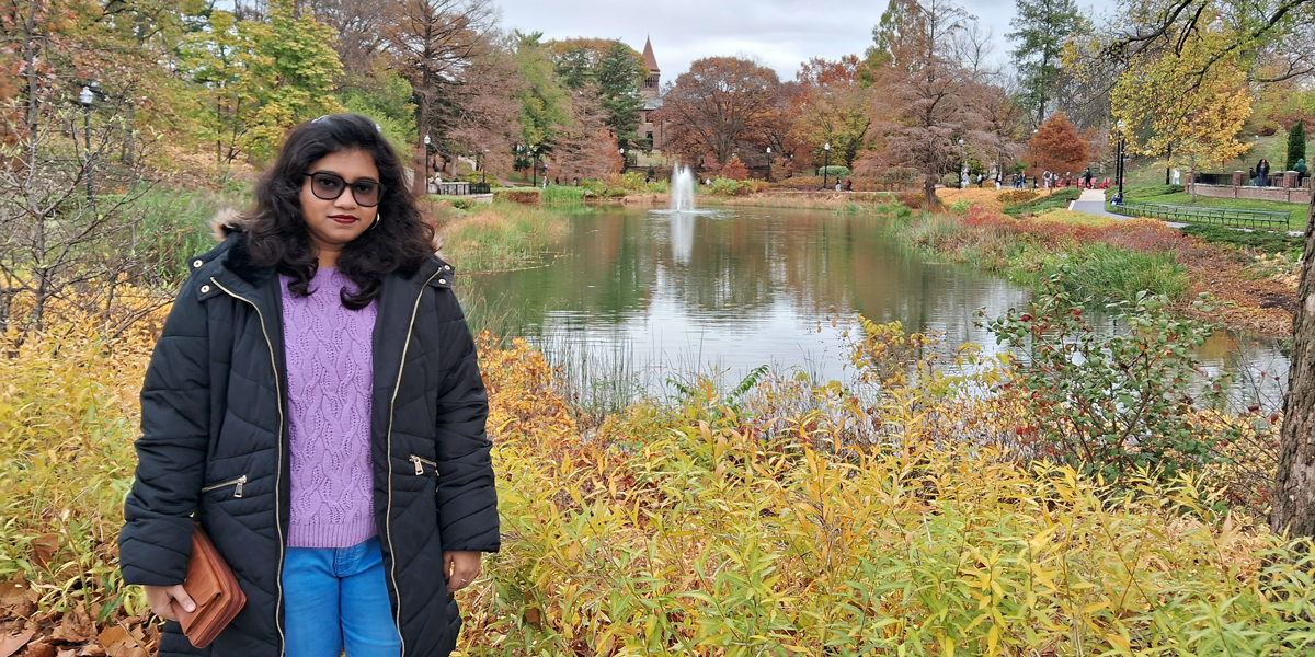 Woman wearing sunglasses poses by Mirror Lake at Ohio State