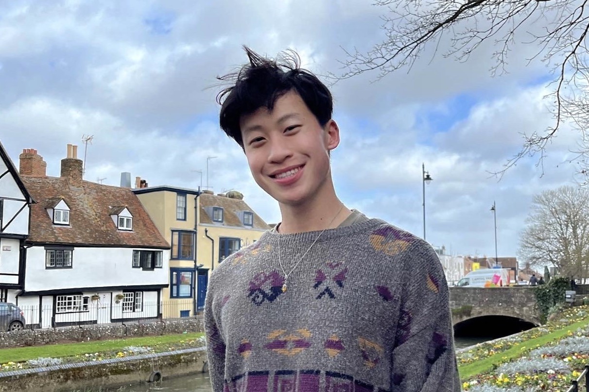 Young man poses in front of European canal and buildings