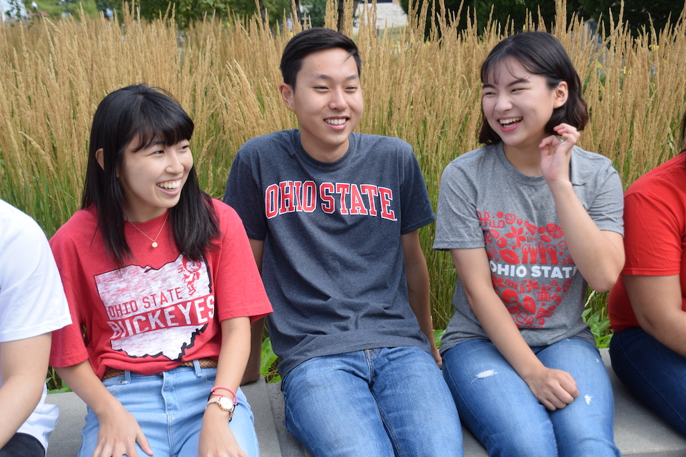 Three students sitting together while laughing.