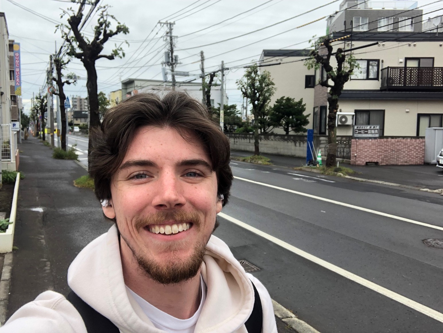 Male smiling on a street with buildings in background