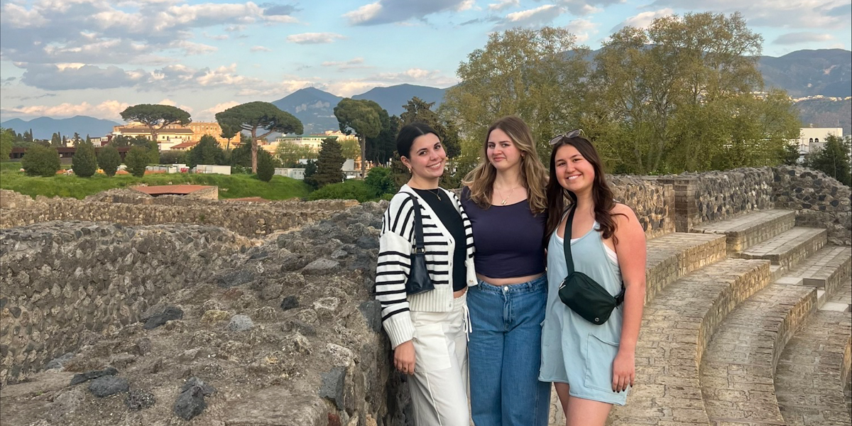 Three women pose outside in Italy.