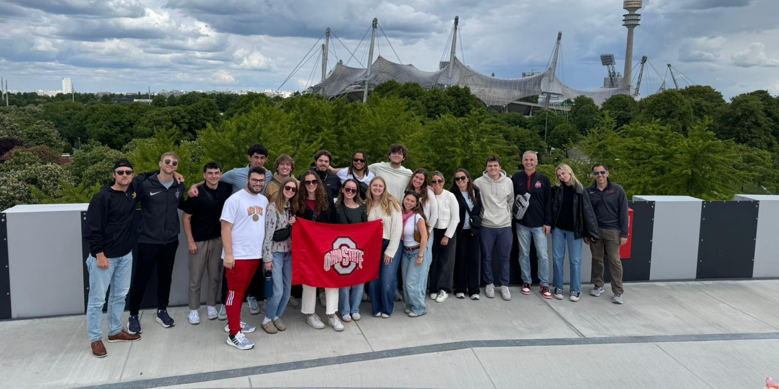 students posing with an Ohio State flag in front of a stadium