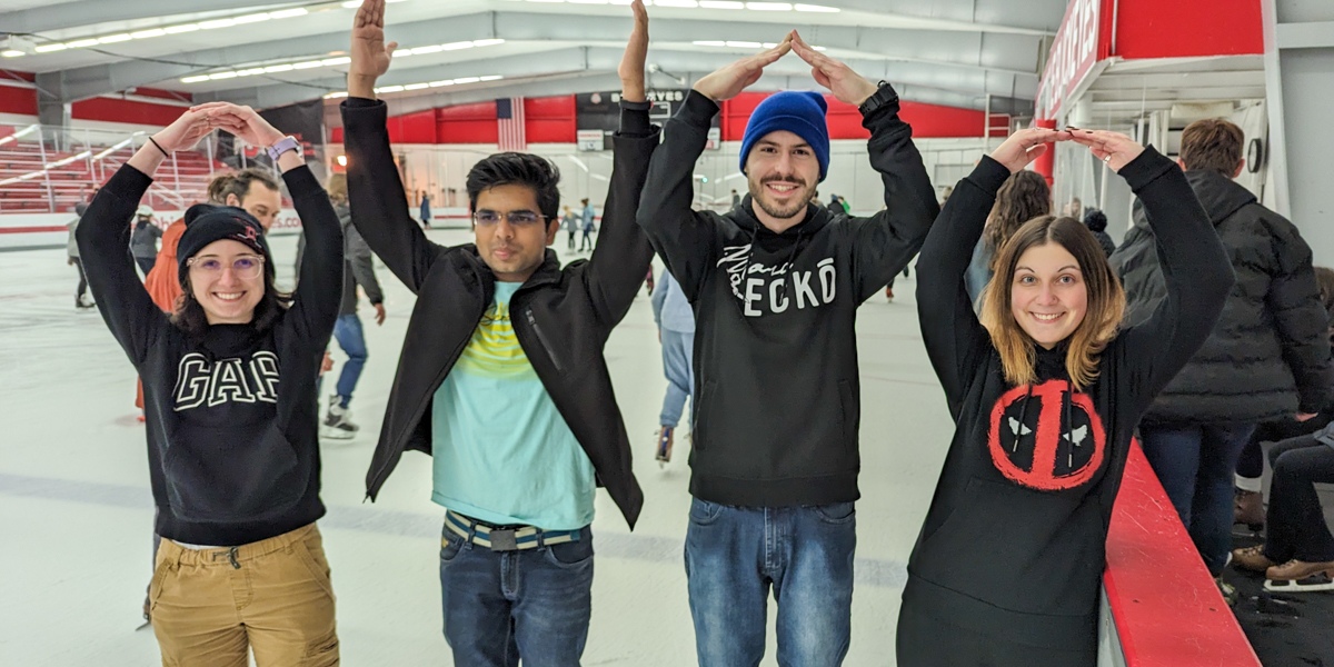 Four people spelling out O-H-I-O with their arms.