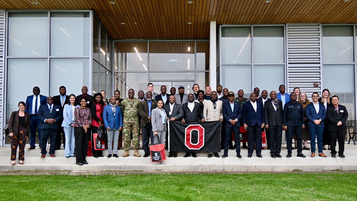 Very large group of people in suits and business clothing gather on steps outside building.