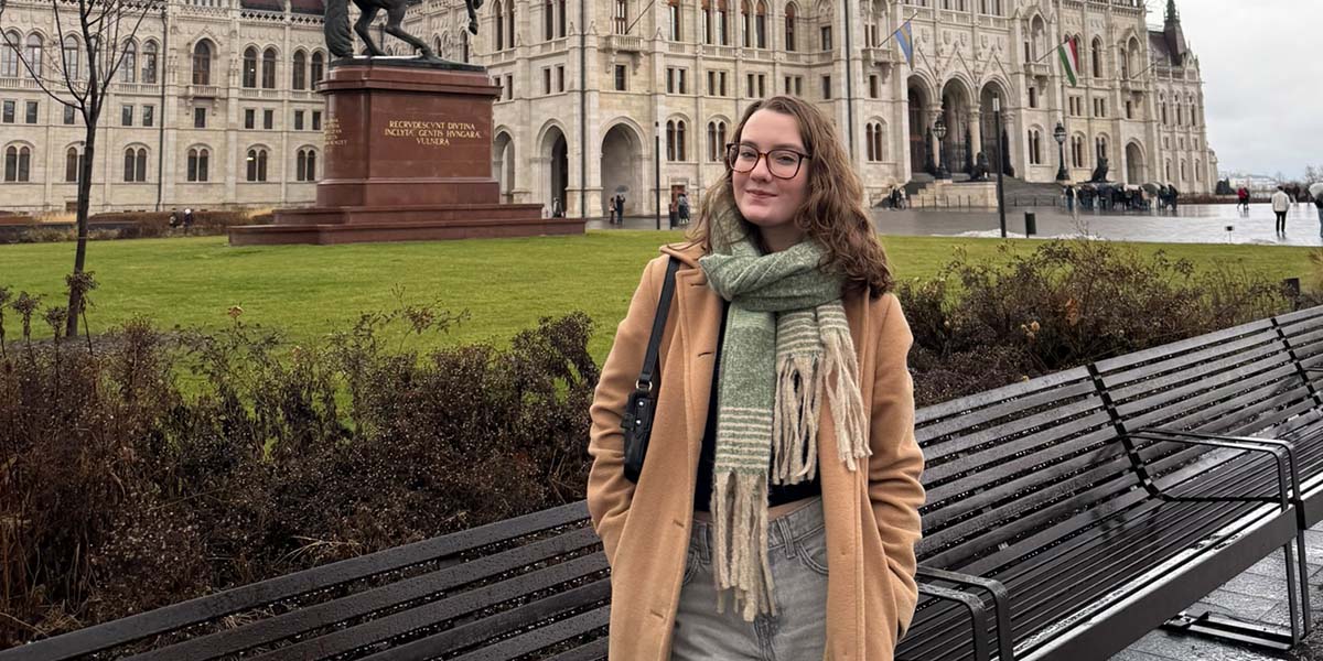 Student posing in front of statue of man on horse