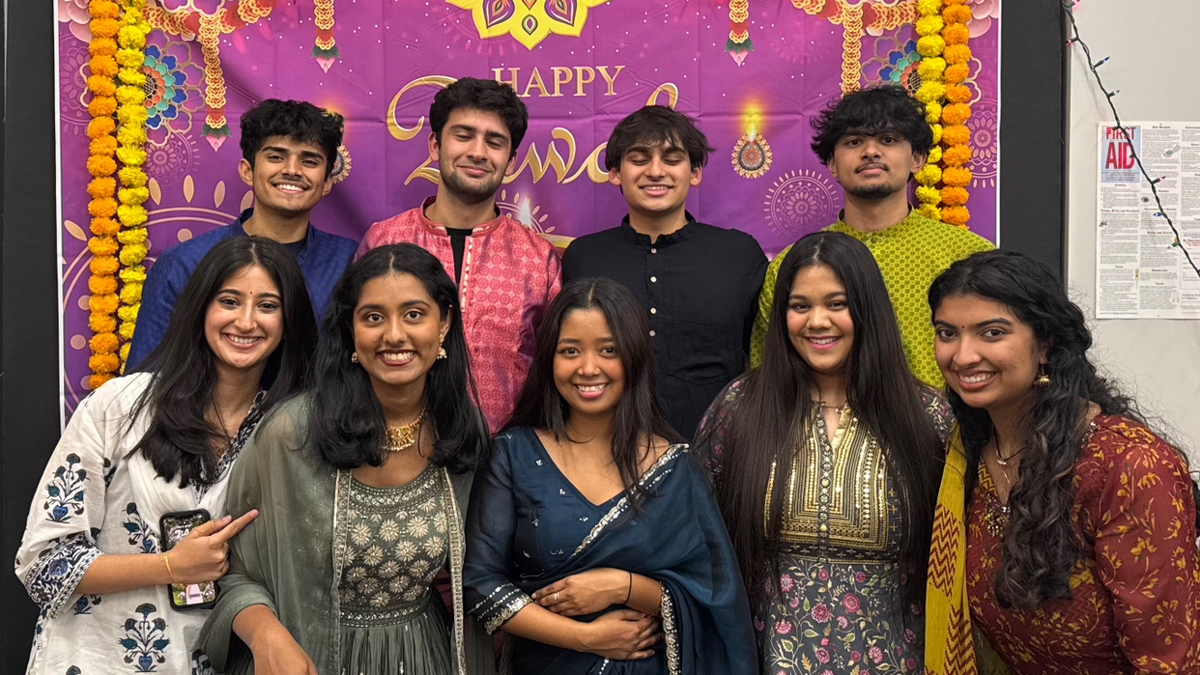 Five women and four men dressed in Indian garb at Diwali event.