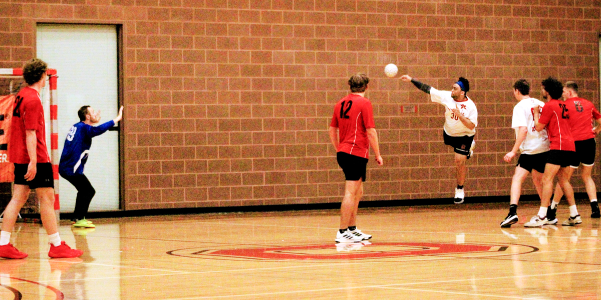 People playing team handball in a gym.