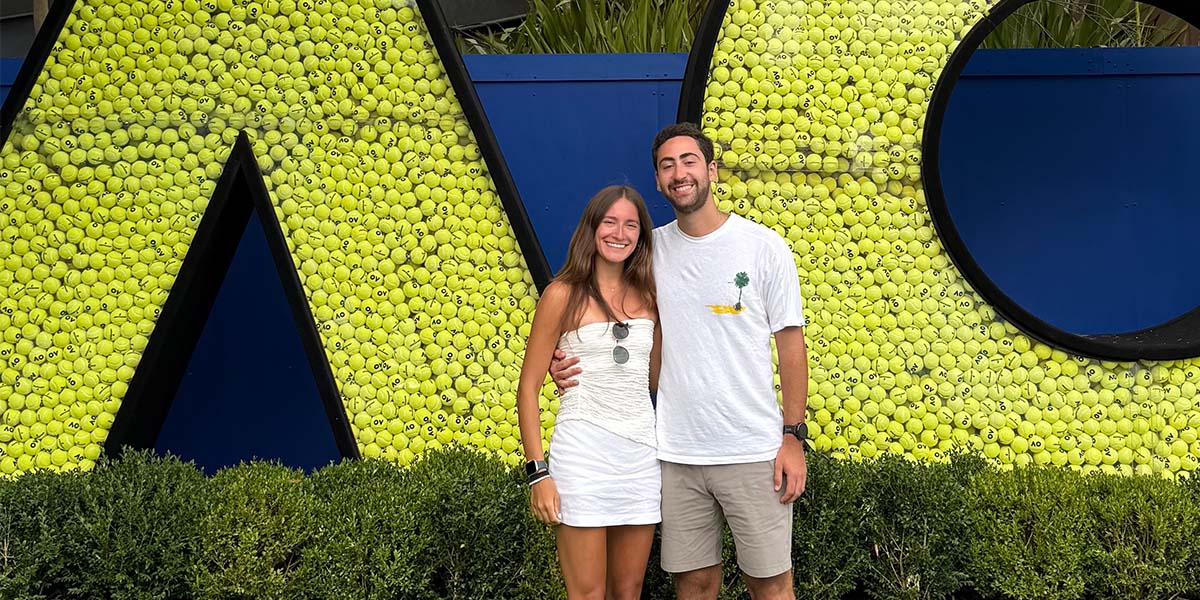 Two people posing at a sign for the Australian Open