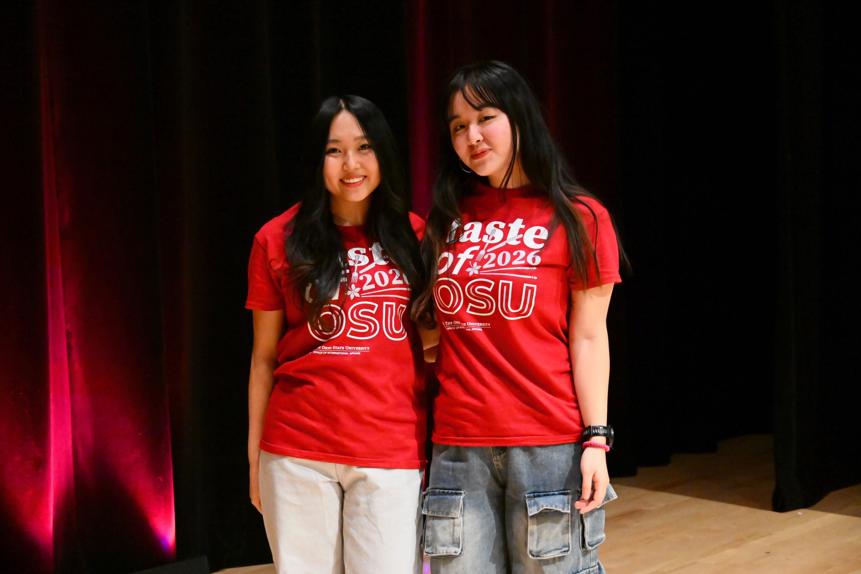 Two students standing on stage in the Performance Hall wearing Taste of OSU t-shirts