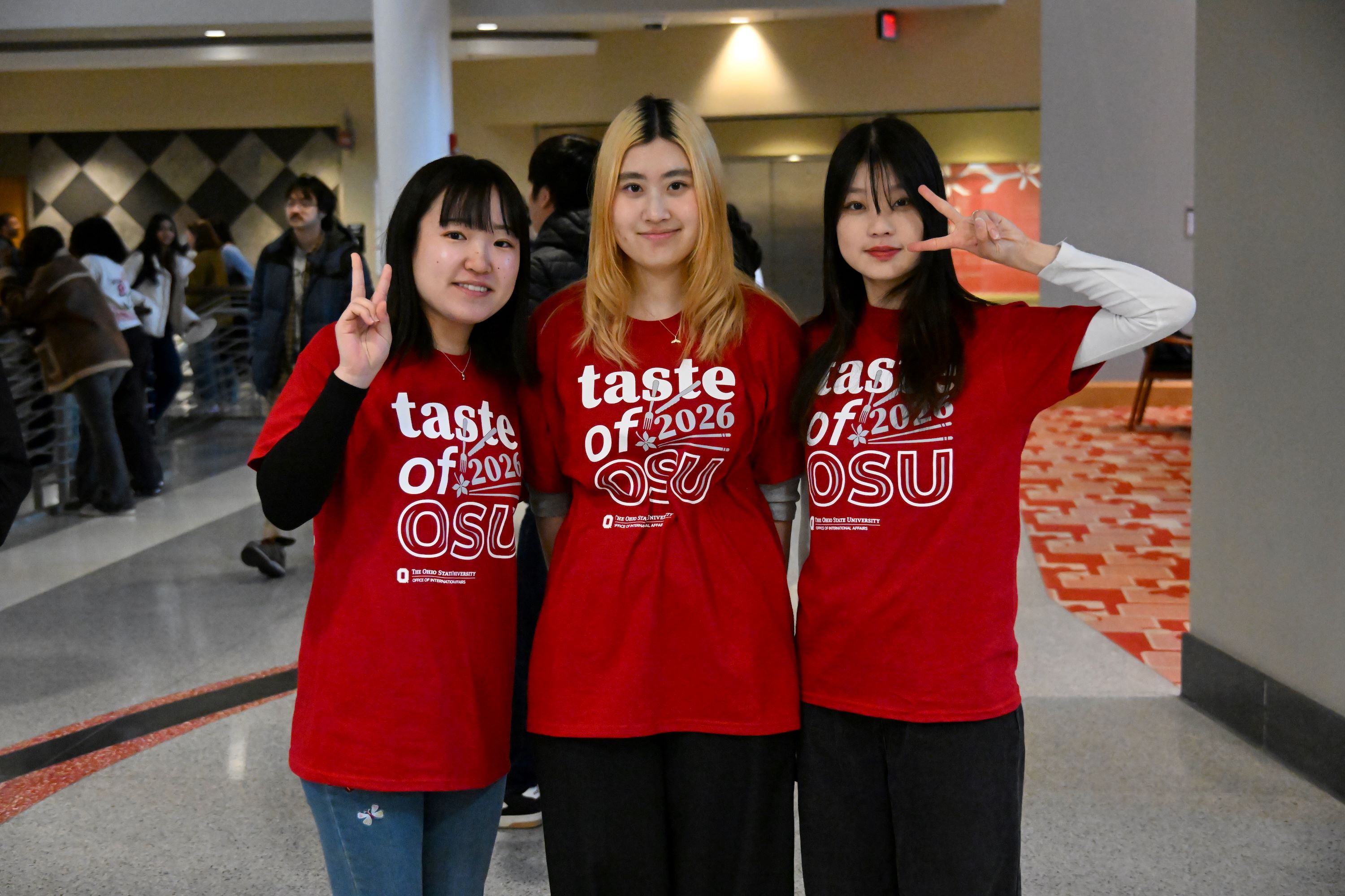 Three students standing in the Ohio Union wearing Taste of OSU volunteer t-shirts
