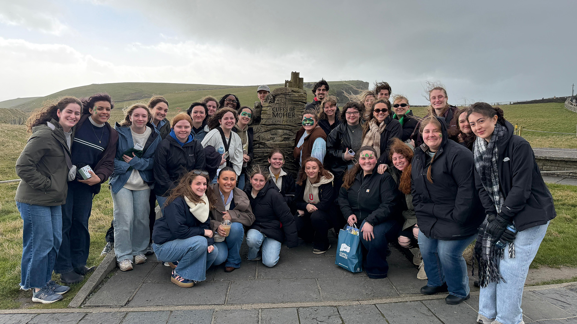 Students posing near a stone on a countryside