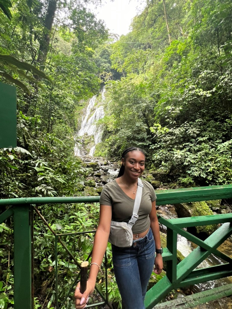 Young woman smiling in front of waterfall on a bridge