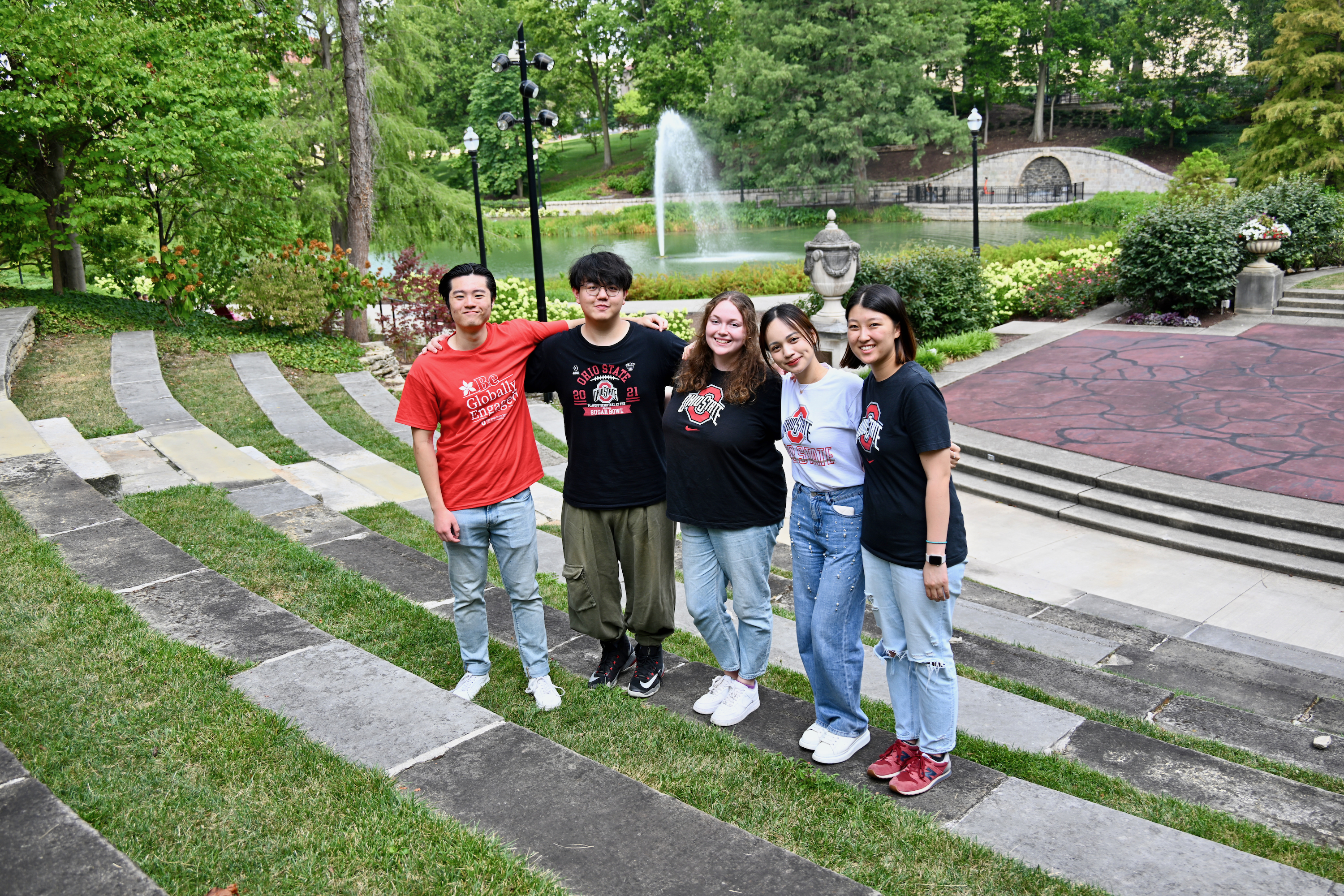 Students in Ohio State global engagement tee shirts standing by mirror lake