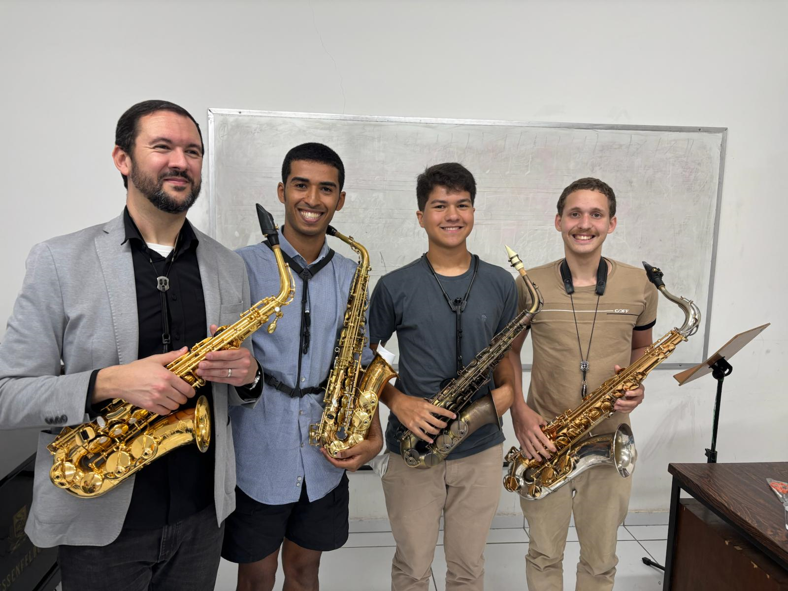 Four students stand with a saxophone in their music program