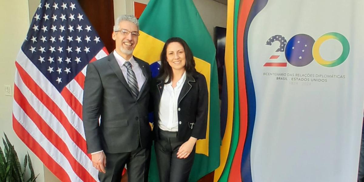 Leite with Jane Aparecido standing in front of the Brazil and United States flags.
