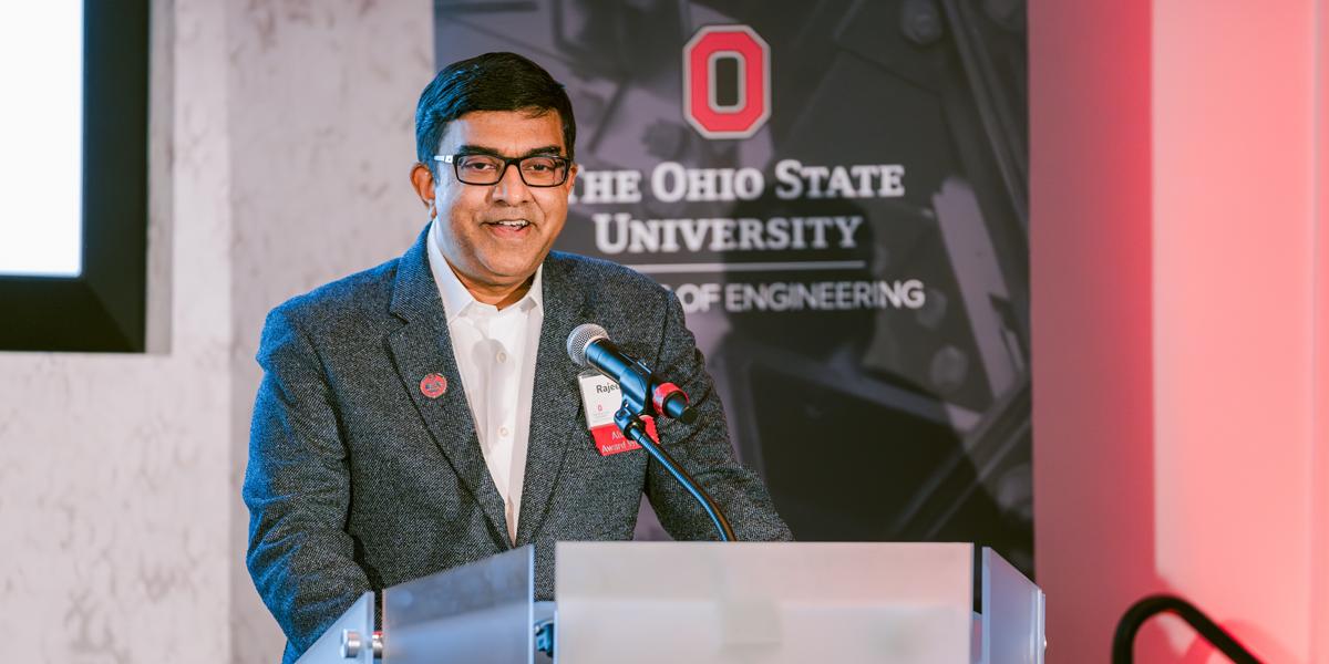 Man wearing glasses speaks at a podium