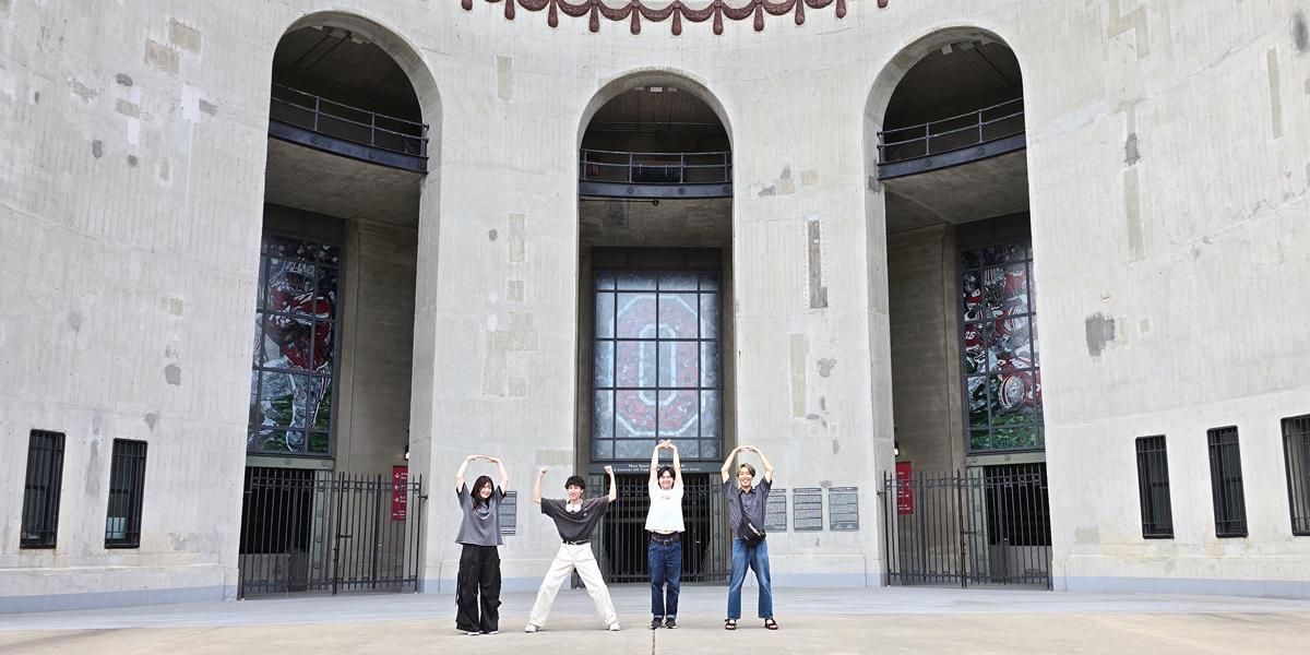 Four students spell O-H-I-O in front of Ohio Stadium