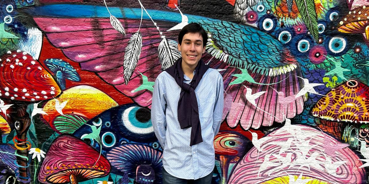 Young man poses in front of colorful mural in Brazil