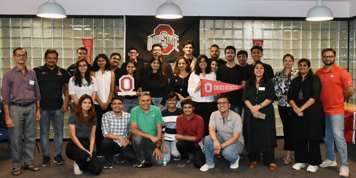 The sendoff event attendees smile as a group while looking at the camera.