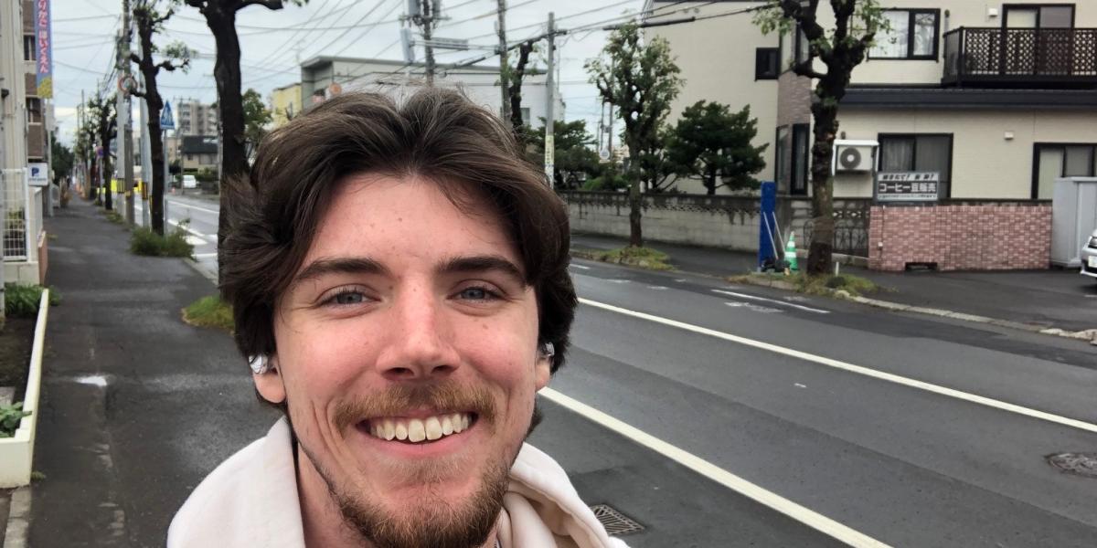 Male smiling on a street with buildings in background