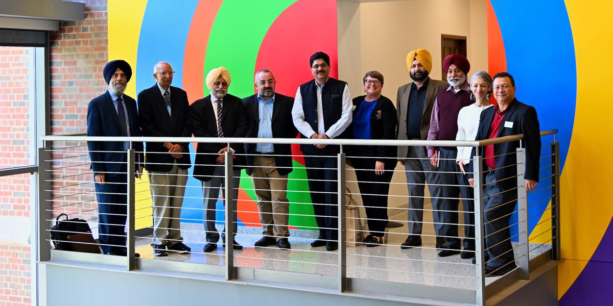 Group of men and a woman pose for photo inside building.