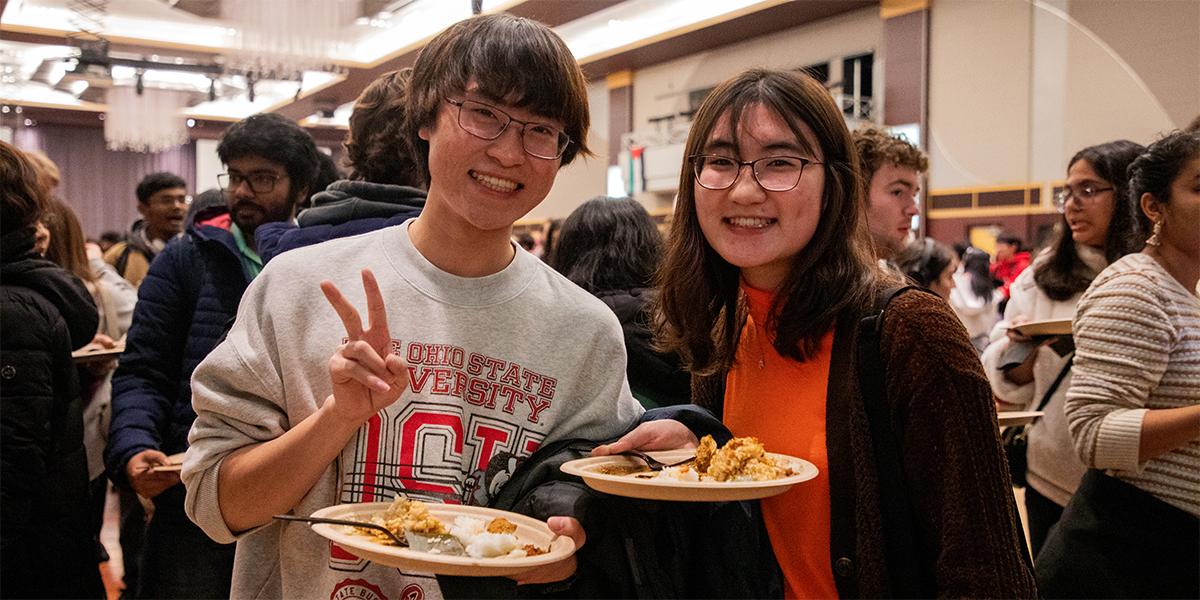 Two people eating food from Taste of OSU 2024