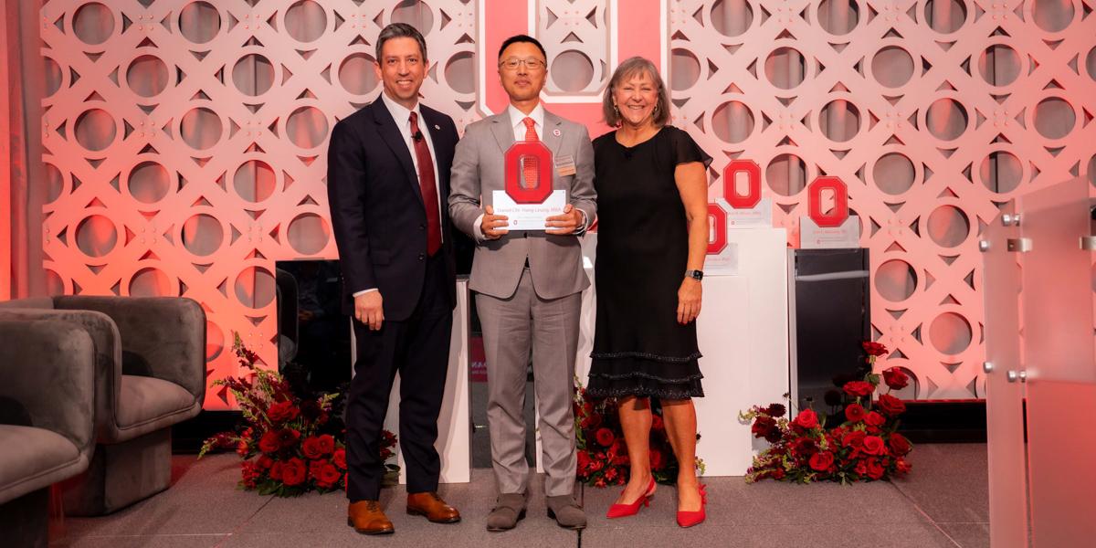 Two men and a woman on stage at awards ceremony