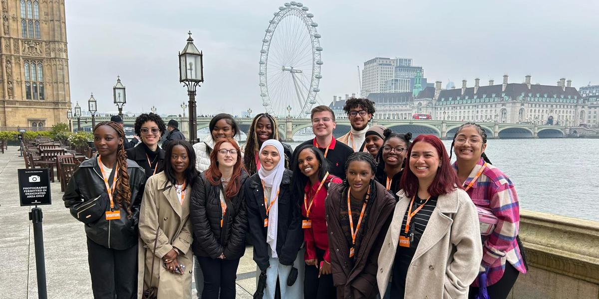 Group of people posing for a photo in front of the London Eye and Westminster Bridge.