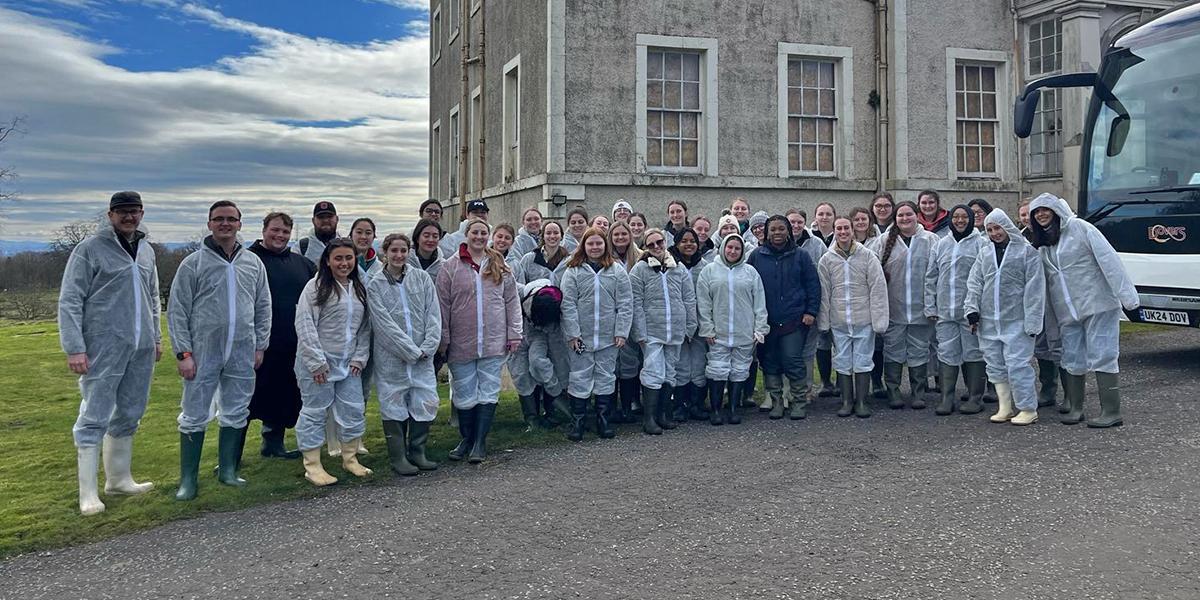 Students standing in lab gear in front of lab
