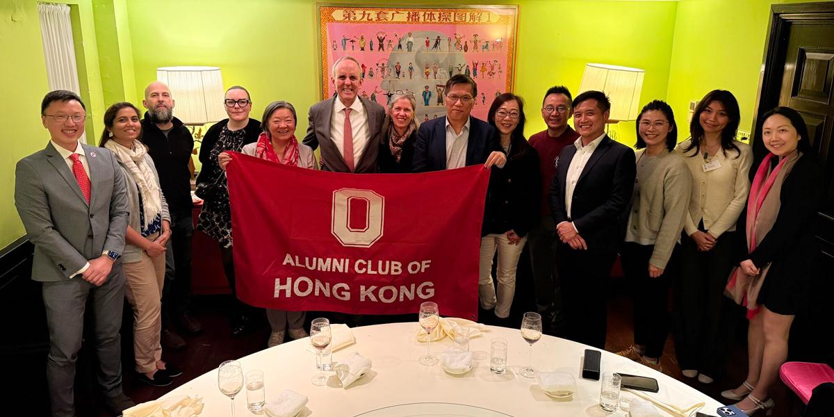Group of people pose for photo holding Ohio State alumni flag.