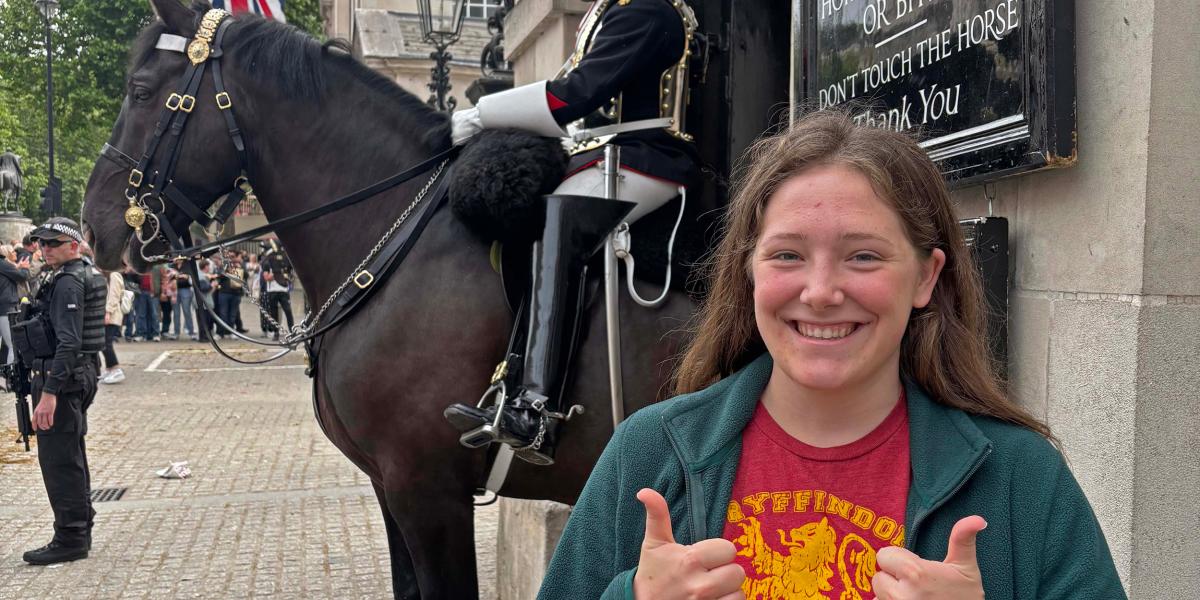 student in front of horse guard in London