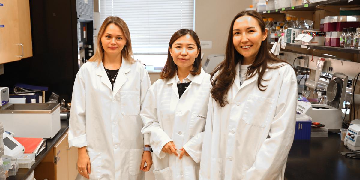 Three women in lab coats in a laboratory setting.