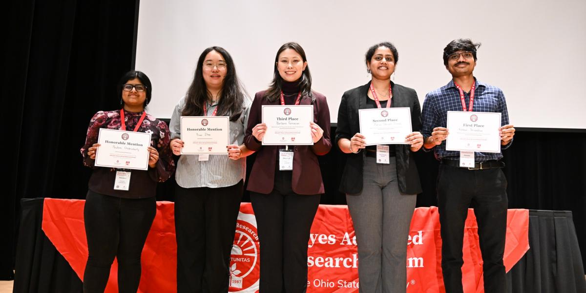 Five students holding up certificates on a stage