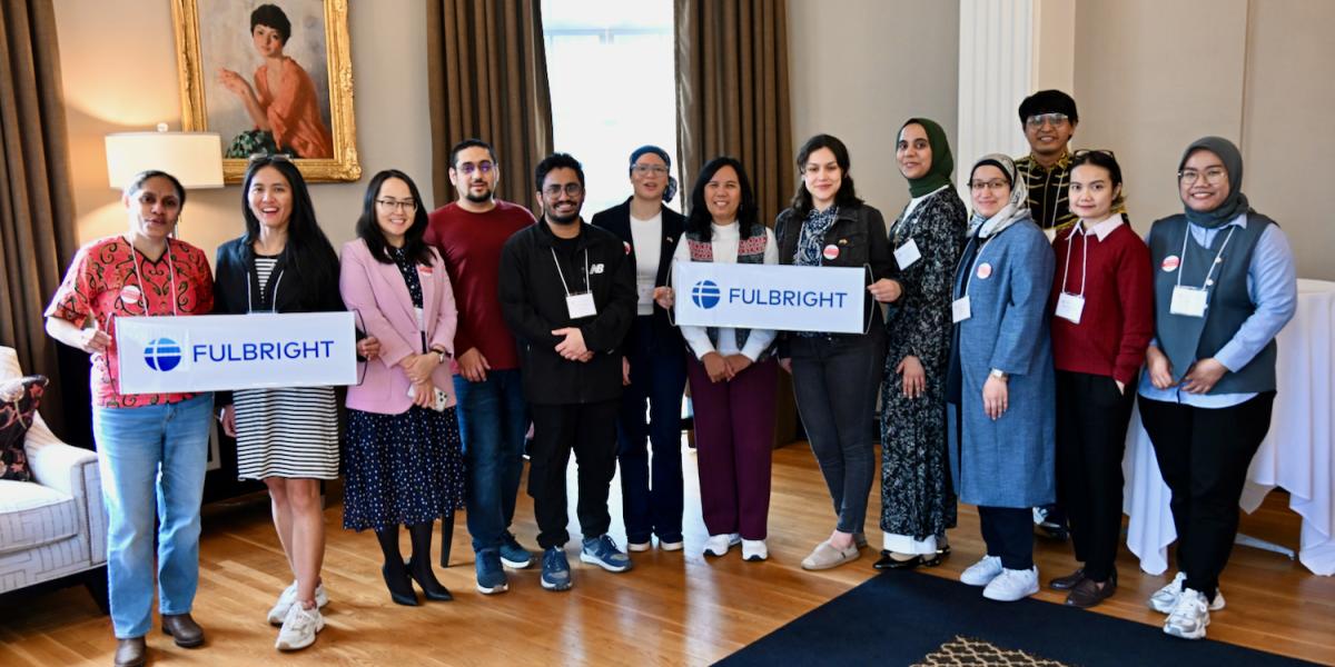 Men and women pose for group photo holding two Fulbright banners.