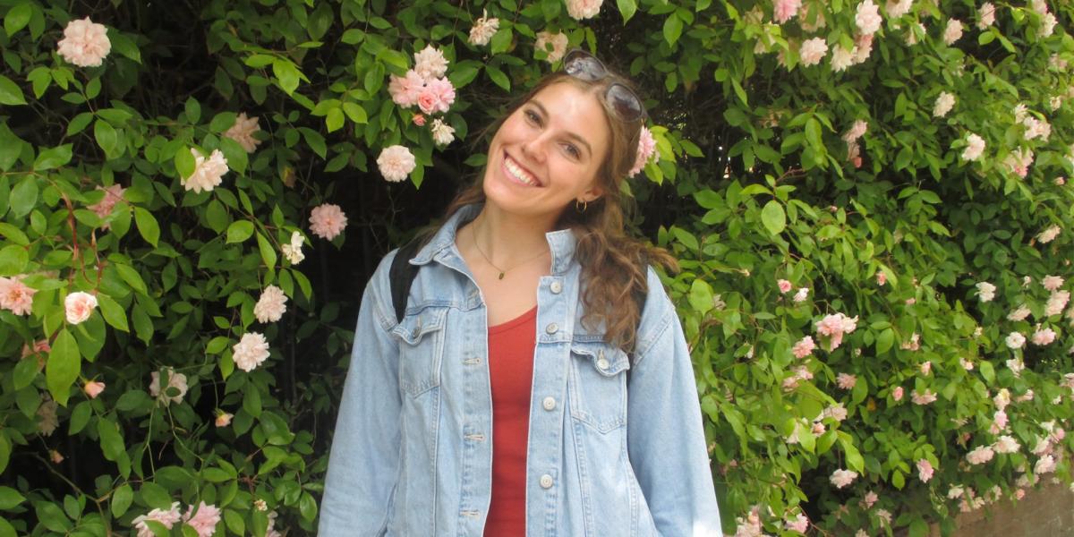 Student in front of shrub and flower wall