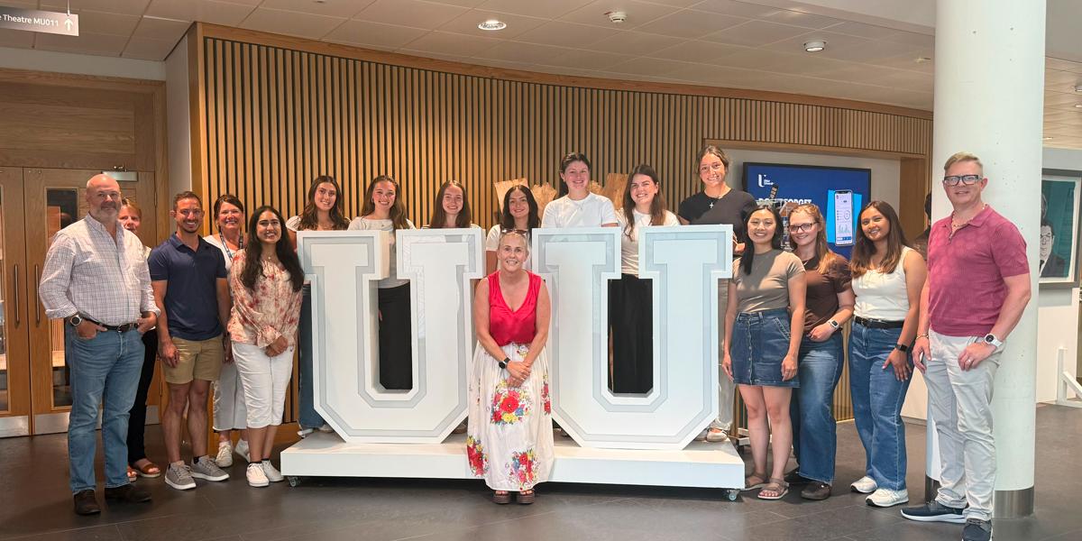 Students and faculty pose by UU sign.