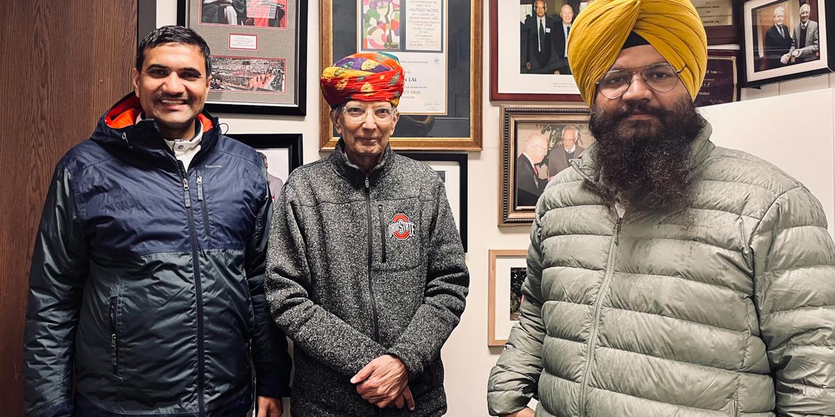 Three men pose indoors.