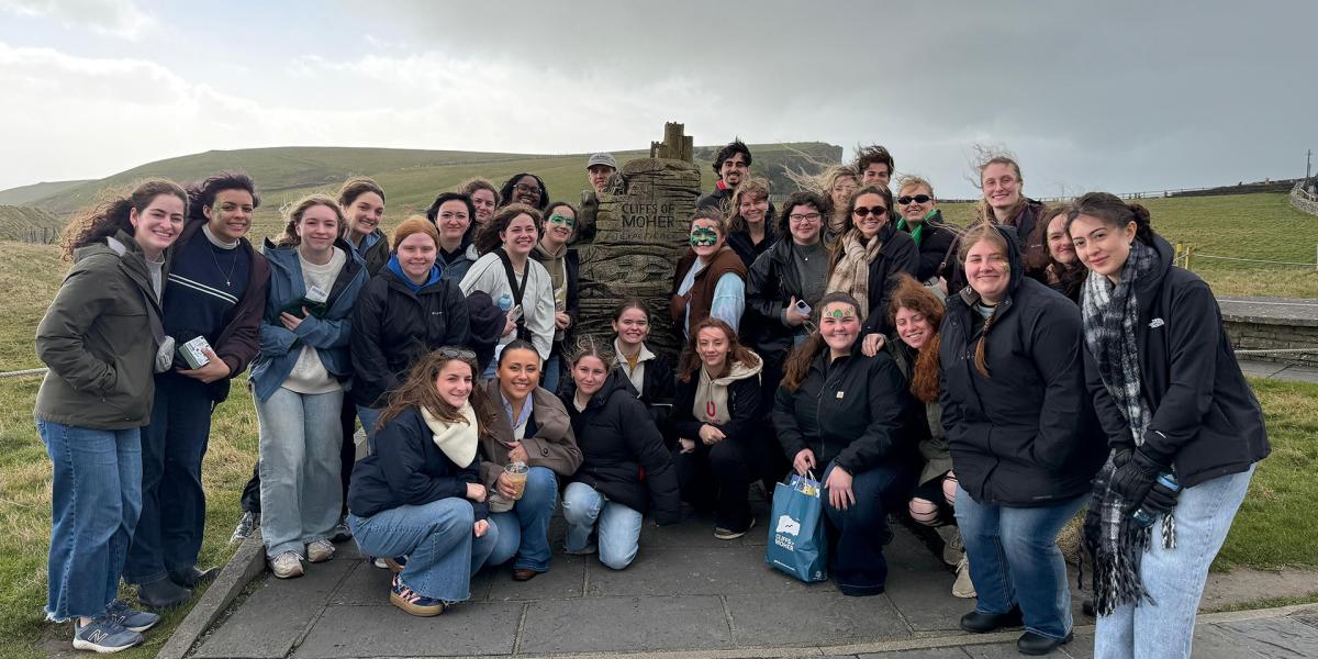 Students posing near a stone on a countryside