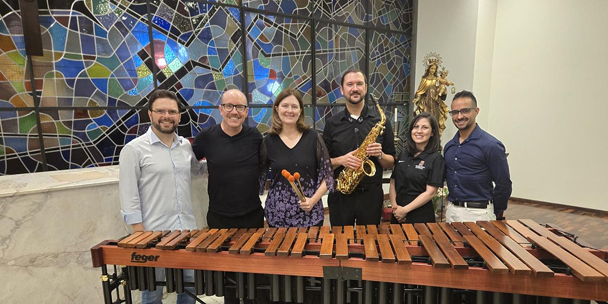 The residency delegation stands behind a marimba.