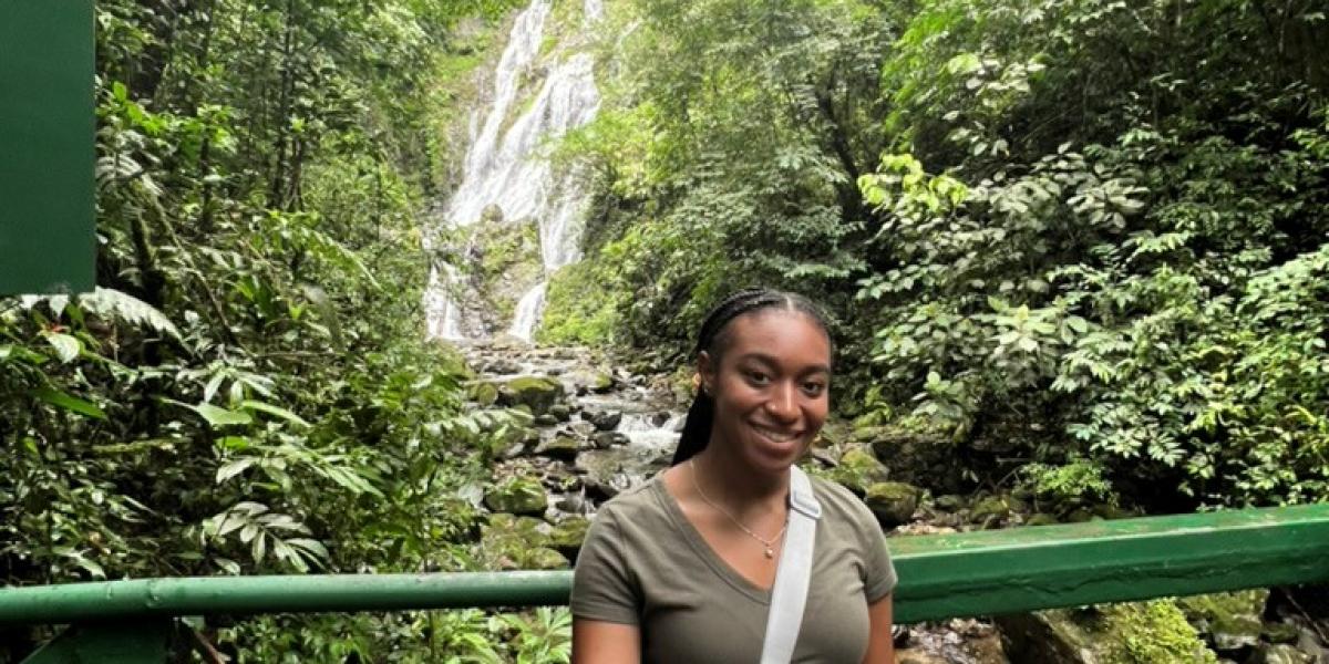Young woman smiling in front of waterfall on a bridge