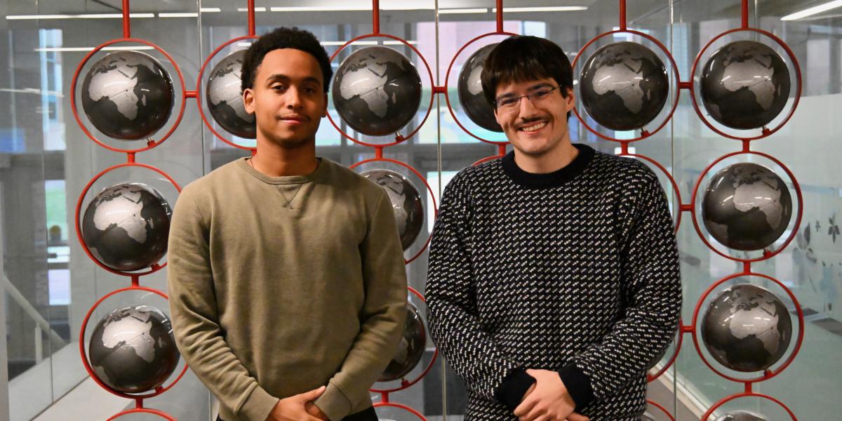 Two students pose in front of globes