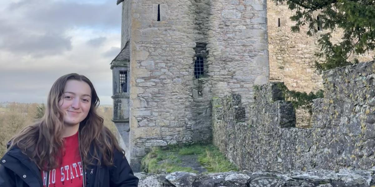 Young woman poses in front of Irish castle