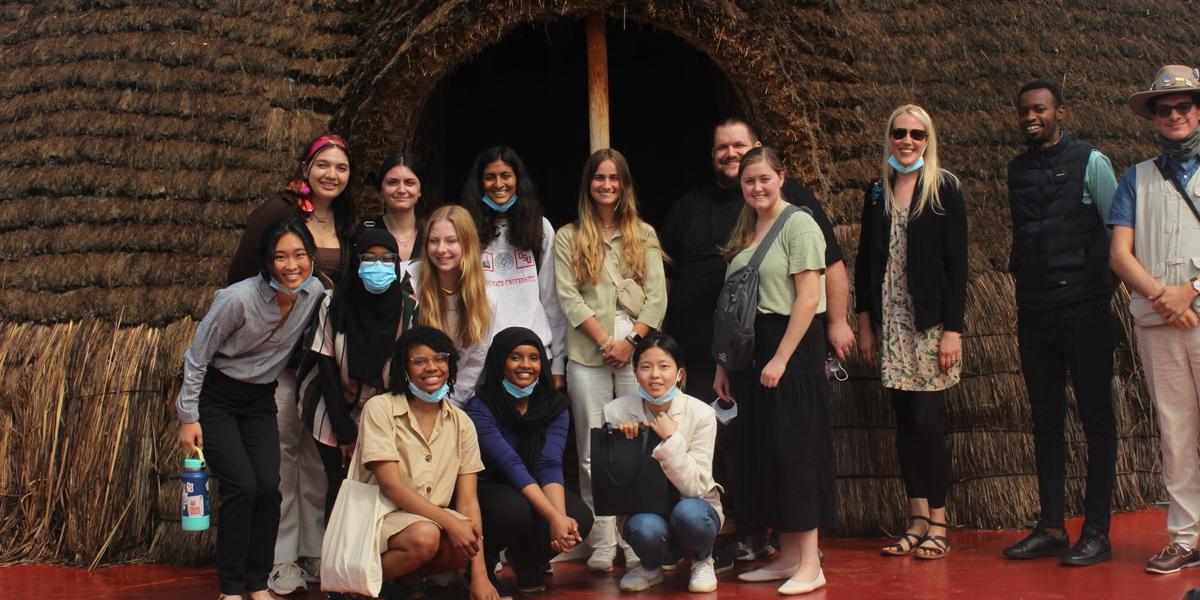 Students outside of a hut