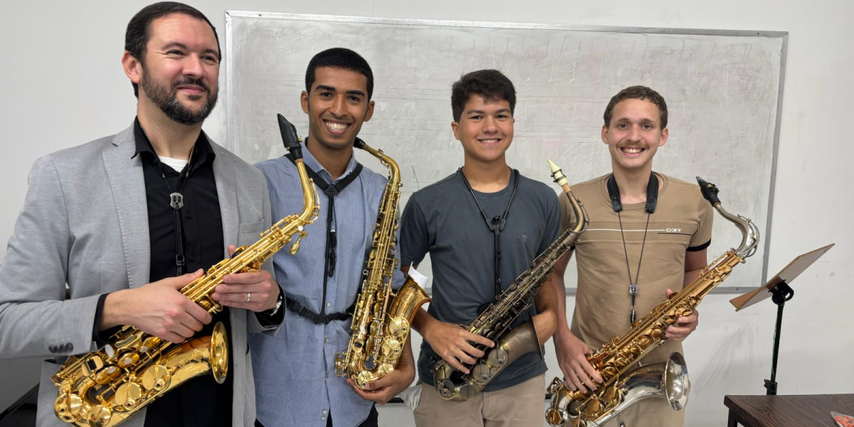 Four students stand with a saxophone in their music program