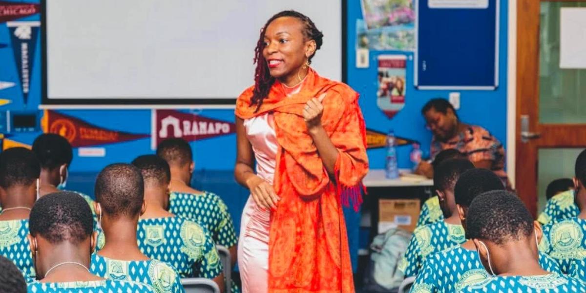 Woman in colorful clothing speaking in a classroom of children.