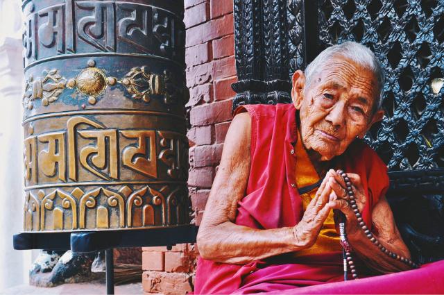 elderly woman sitting in front of temple
