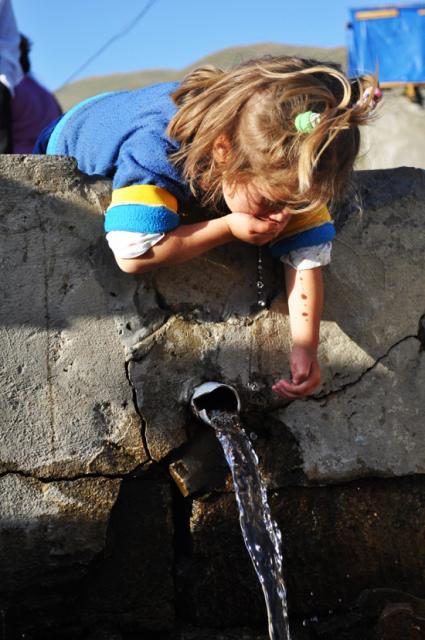 little girl drinking out of water faucet